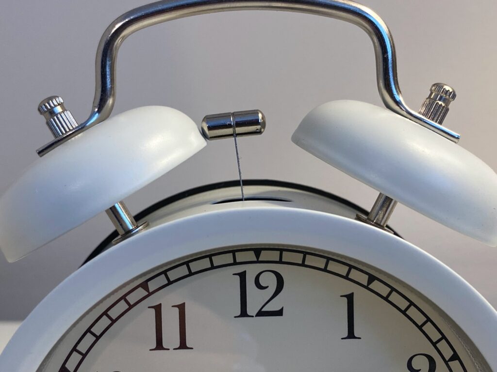 Top half of a white colored classic ringing alarm clock is visible.